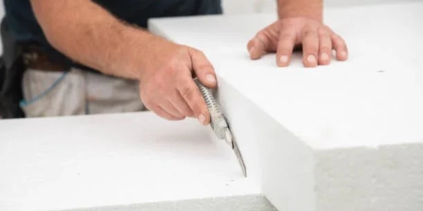 Installer cutting a 4x8 PVC ceiling sheet with a utility knife on a workbench showing clean score line before snapping the panel for a dust free cut Installer cutting a 4x8 PVC ceiling sheet with a utility knife on a workbench showing clean score line before snapping the panel for a dust free cut